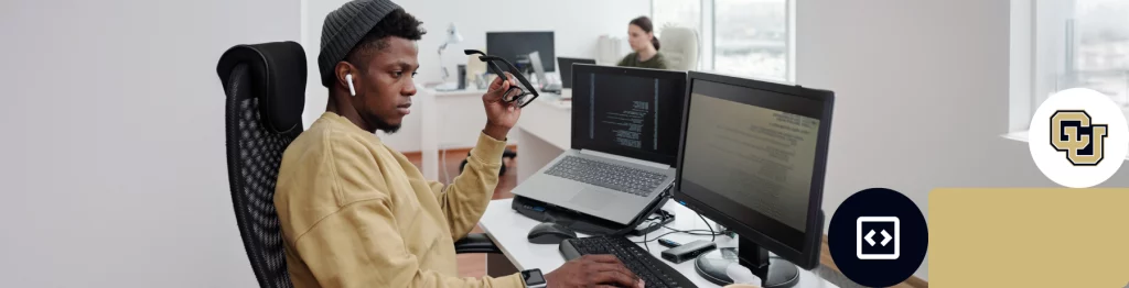 Person coding at a desk with multiple monitors and University of Colorado logo